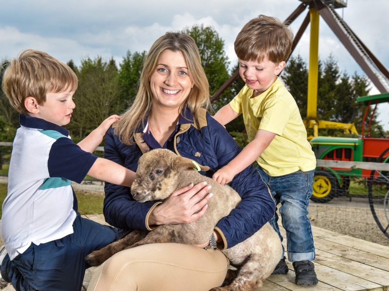 Annabelle St John from Lightwater Valley petting a lamb, with Jack and George Oswald.